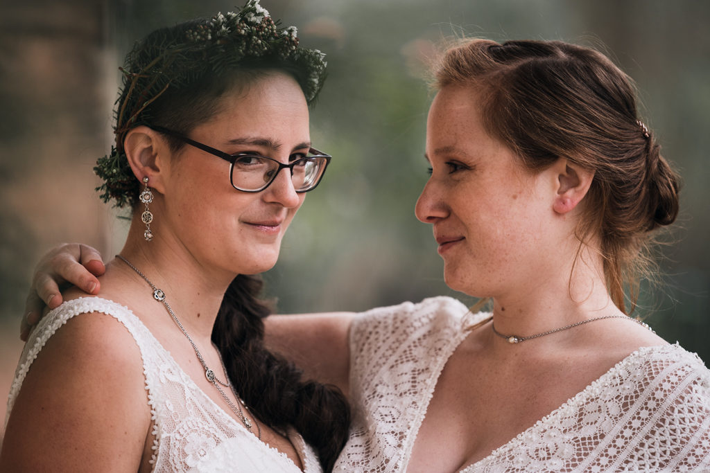 Photo d'un couple de femmes, celle de gauche regarde l'objectif, celle de droite regarde celle de gauche