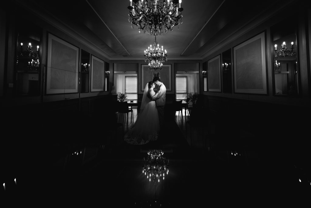 Un couple se tient face-à-face au centre de l'image, sous un chandelier.