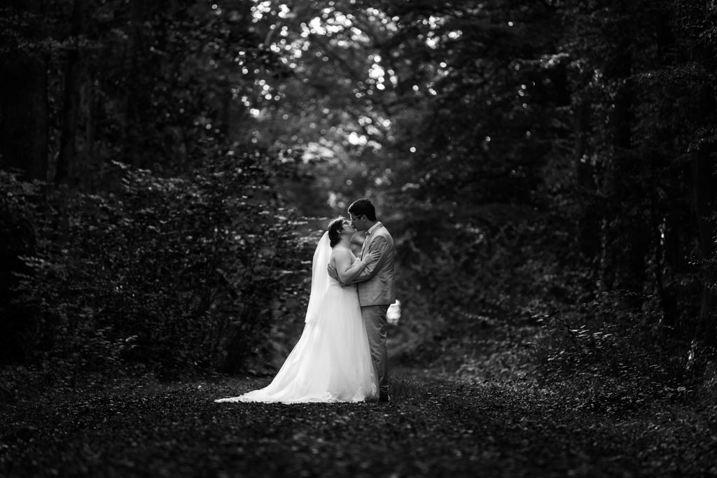 Couple de mariés s'embrassant sous les arbres