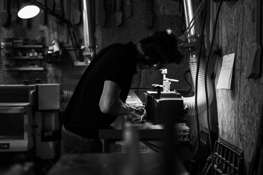 luthier donnant sa forme à un manche de basse