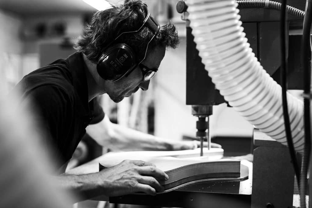 luthier creusant dans le bois pour fabriquer une basse, photo de reportage