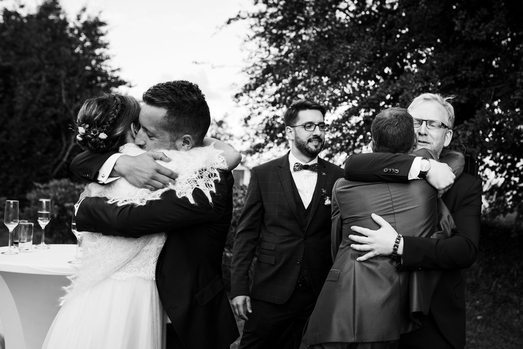 Couple de mariés serrant des invités dans leurs bras