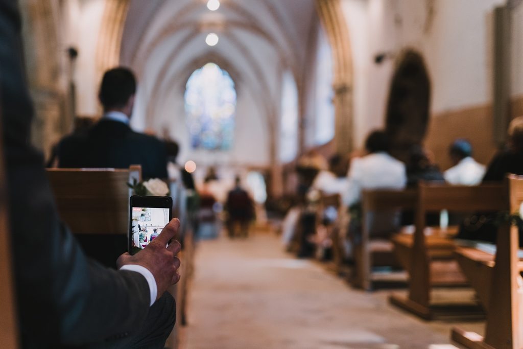 Invité de mariage en train de photographier avec son smartphone pendant l'église