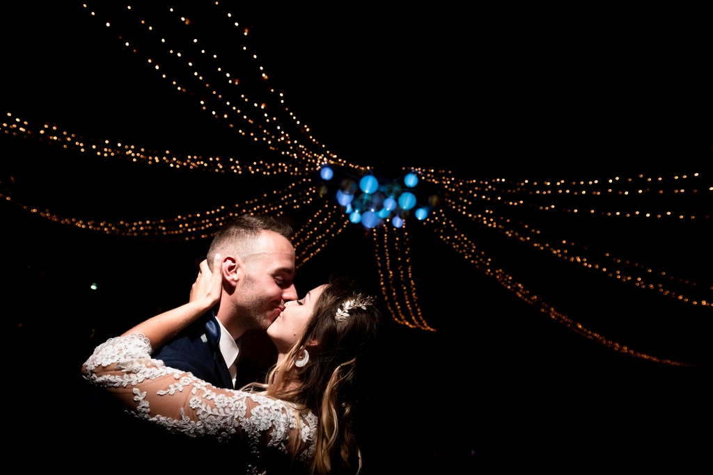 La première danse vue par un photographe de mariage. Le plafond lumineux se devine derrière le couple qui s'embrasse pendant leur première danse de mariage