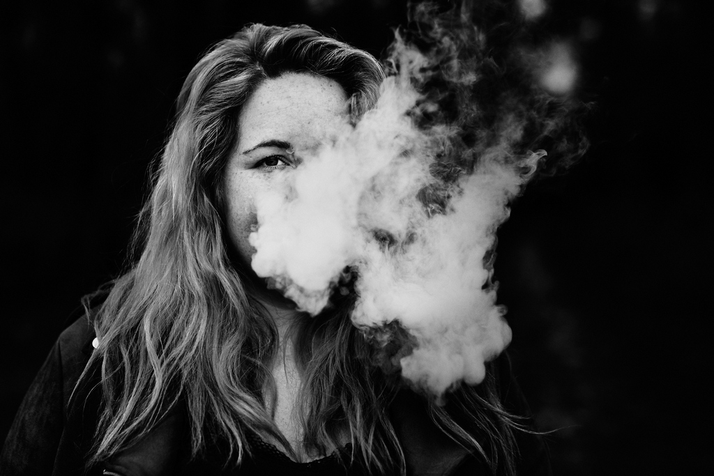 Regard d'une femme se dévoilant à travers la fumée d'une cigarette électronique
