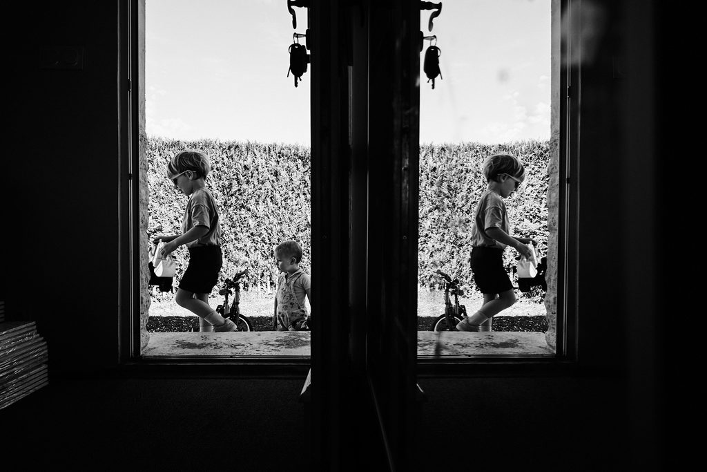 Sur la gauche on voit les deux enfants à travers la porte d'entrée, sur la droite on ne voit que le reflet du plus grand