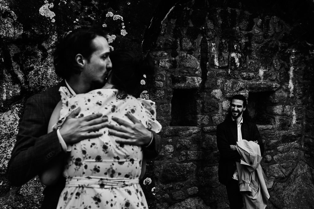 Photo de deux amoureux s'embrassant sous le regard plein de compersion d'un troisième amoureux