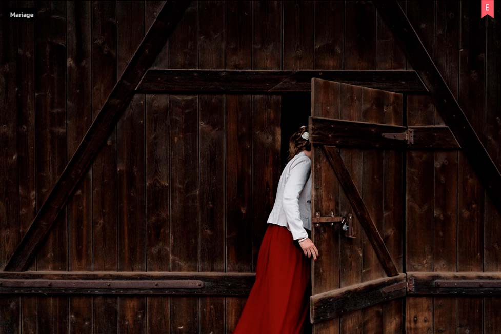 femme avec une robe rouge et un haut blanc entrant dans une grange
