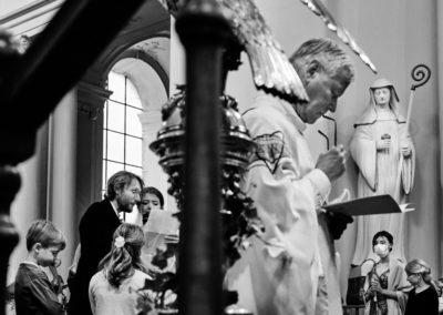 Photo d'un mariage à Gembloux, près de Namur. Différents éléments composent l'image : le prêtre, le couple, les enfants, et une statue