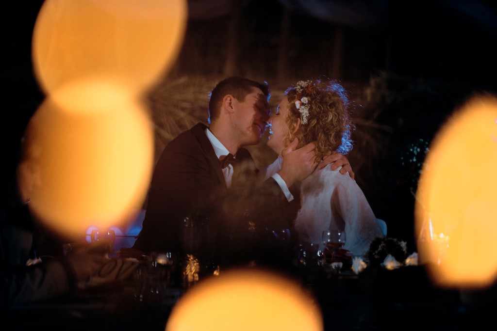 Photo d'un couple s'embrassant pendant le repas de mariage, non loin de Sélestat. Au premier plan des tâches de lumière encadrent le couple
