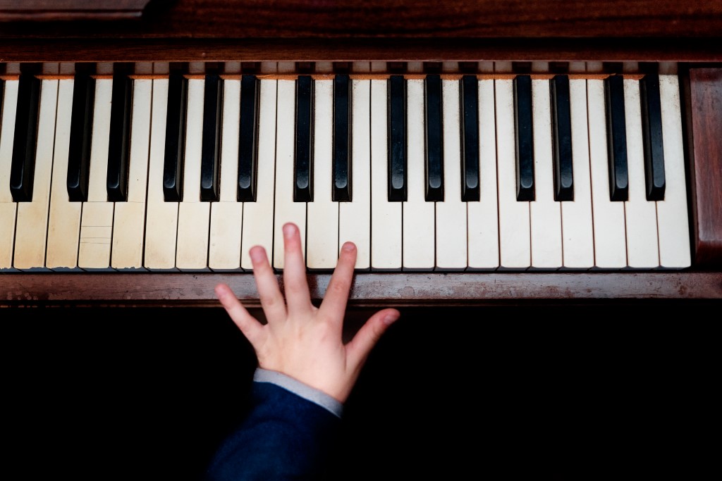 main d'enfant posée sur les touches d'un piano, vu du dessus, photo prise lors d'un reportage famille