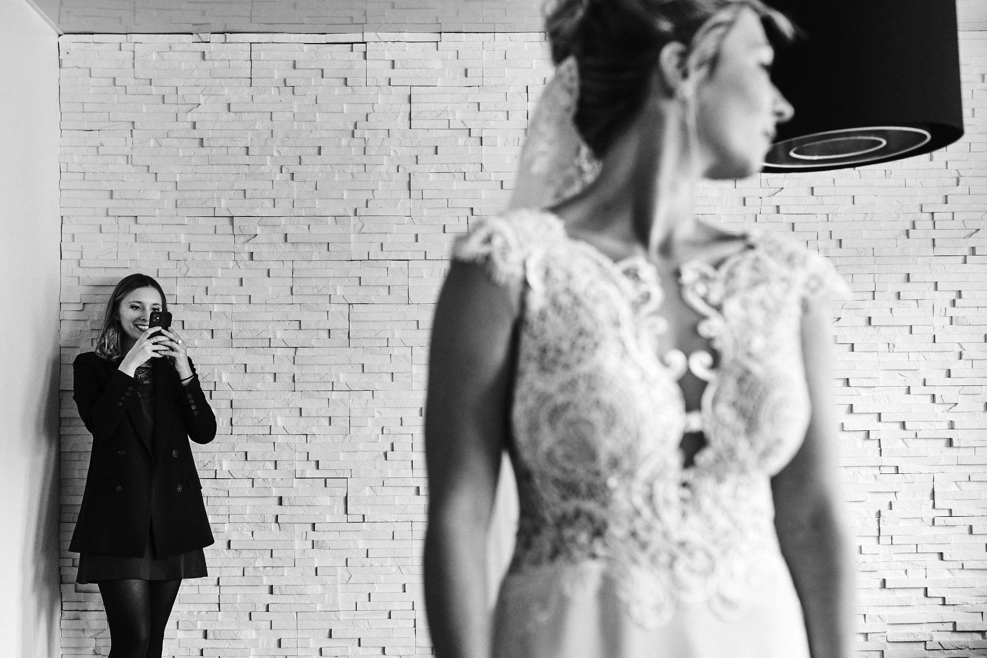 Invitée de mariage photographiant la mariée avec son smartphone à la fin des préparatifs