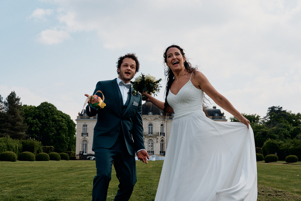 Couple de mariés devant le château de Pont-chevron incitant les invités à les suivre lors de leur sortie de cérémonie laique