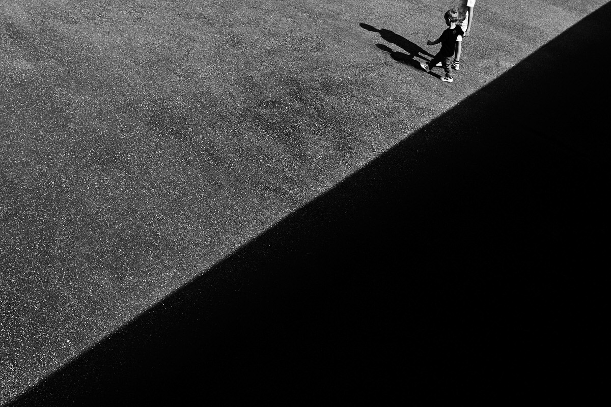Photo d'un enfant avec deux triangles délimités par une ombre au sol