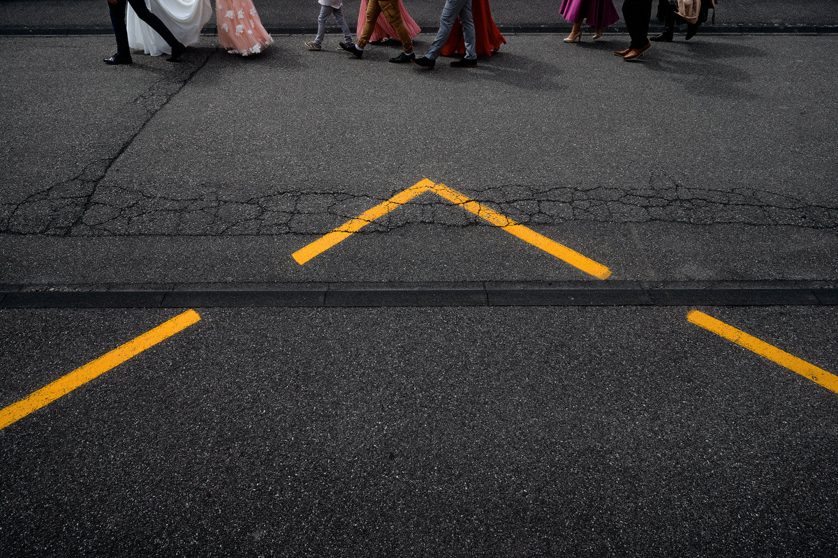 Cortège de mariage à pied, photographié de façon créative, avec juste les pieds en haut de l'image, et un arrêt de bus formant un triangle sur le devant de l'image