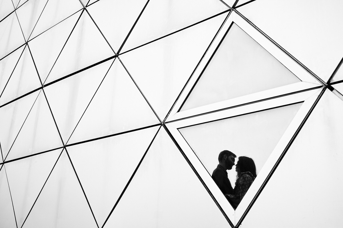 Silhouette d'un couple se reflétant dans un bâtiment composé de triangles à Montpellier