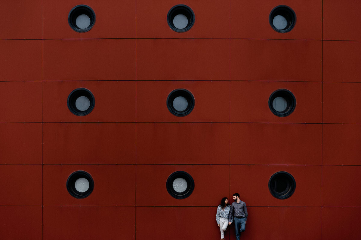 Couple devant un mur rouge, se regardant dans les yeux