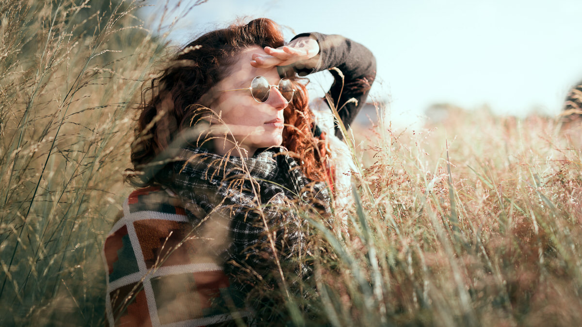 Photo d'une jeune femme rousse dans un champ de hautes herbes regardant au loin