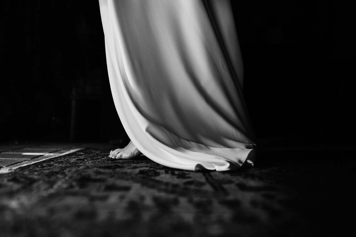 Bas de la robe de la mariée, avec le pied nu de la mariée qui dépasse de la robe pendant l'habillage