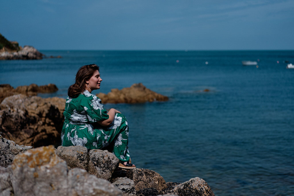 Séance photo lifestyle dans la hague, on voit une femme en robe verte contemplant le paysage sauvage de la hague