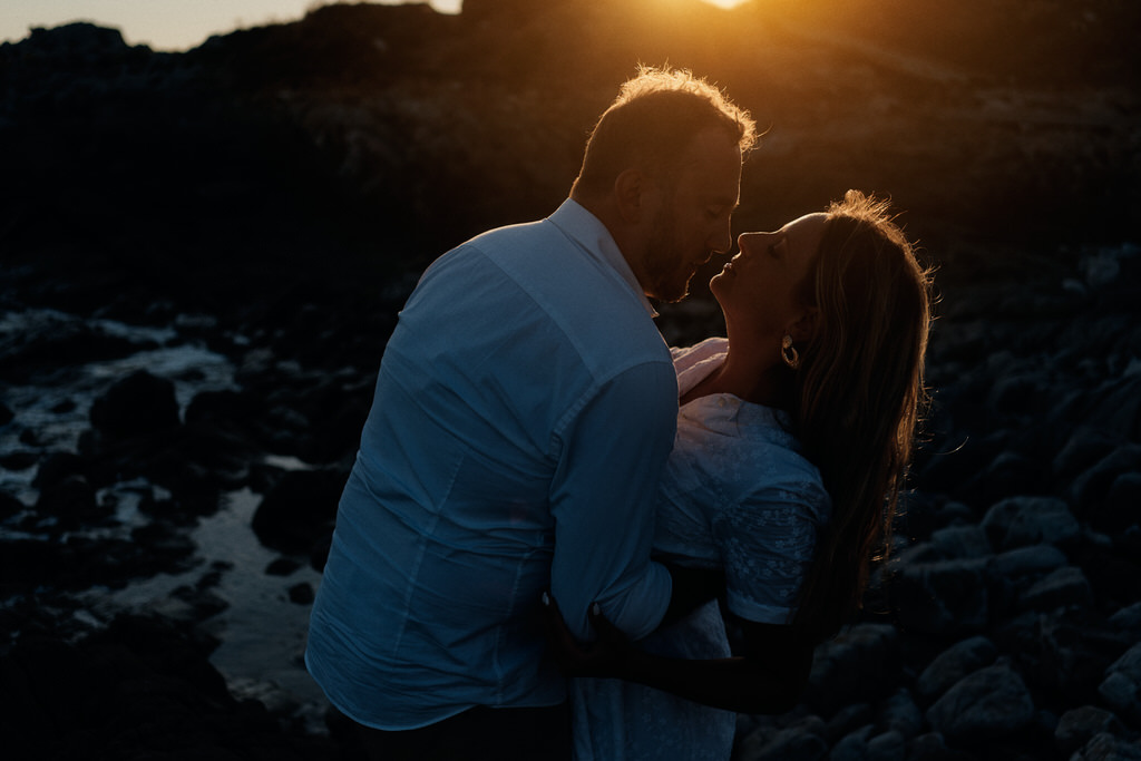 couple s'embrassant, leur silhouette détachée par un filet de lumière créé par la lumière du soleil à contre-jour et le fond sombre